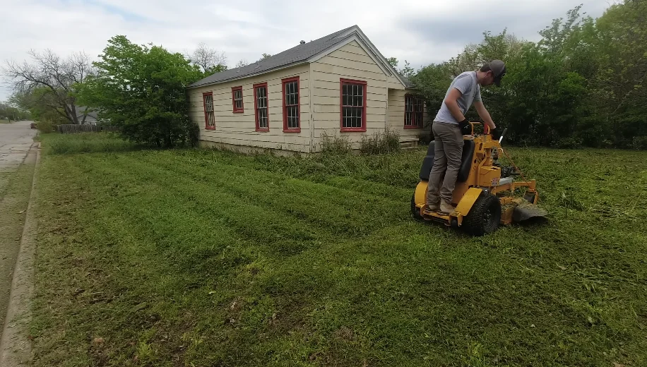 aiken lawn service work — crew member hauling away cleared shrub debris from restoration job